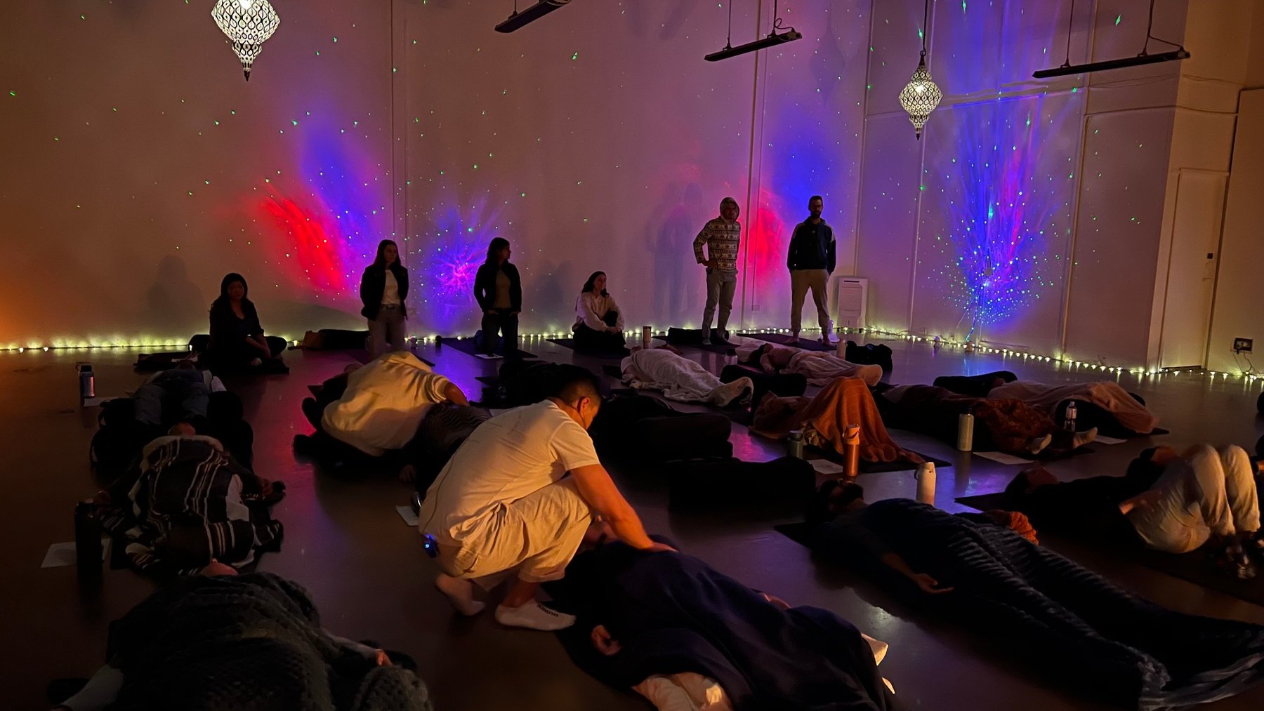 Full group breathwork practice with soft lighting and floor mats