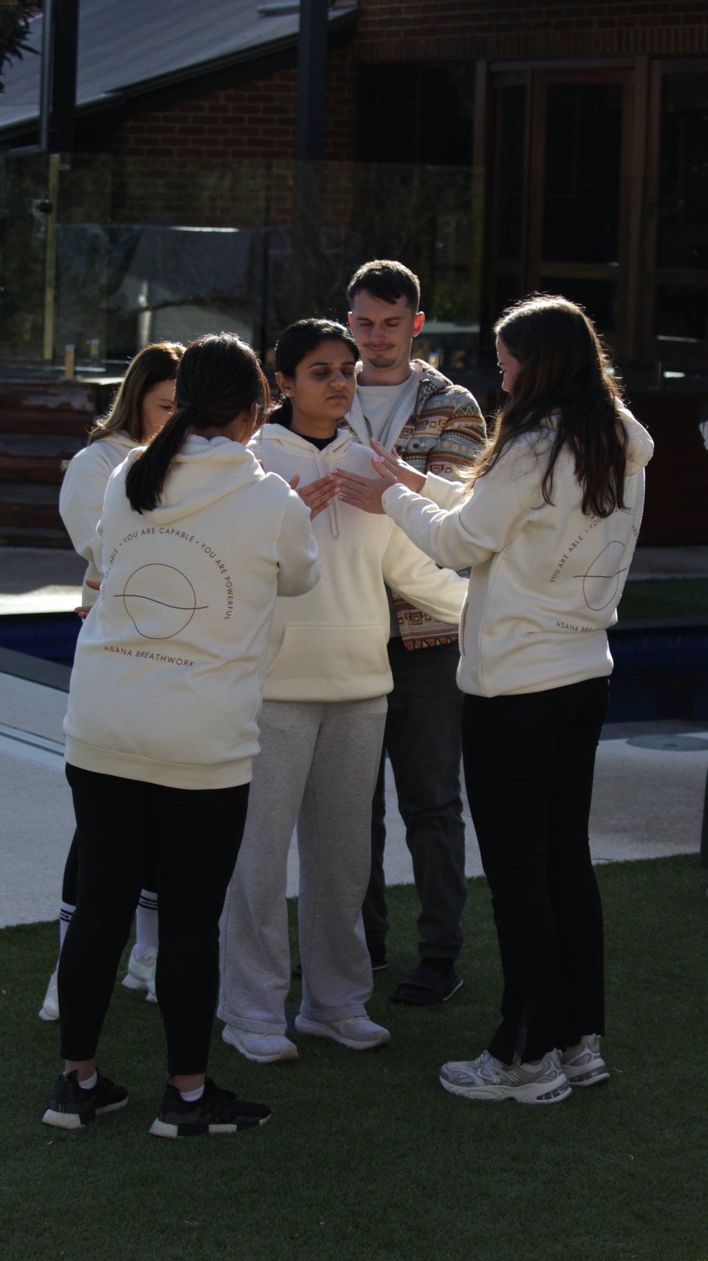 Trainees in a closing circle wearing Asana Breathwork hoodies